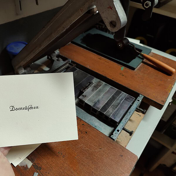 Historische Druckmaschine bei der Arbeit in einer Werkstatt.