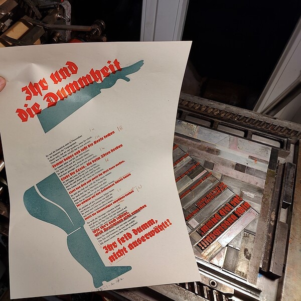 Gedrucktes Plakat mit Titel 'Die und die Dummheit' in einer Druckerei.