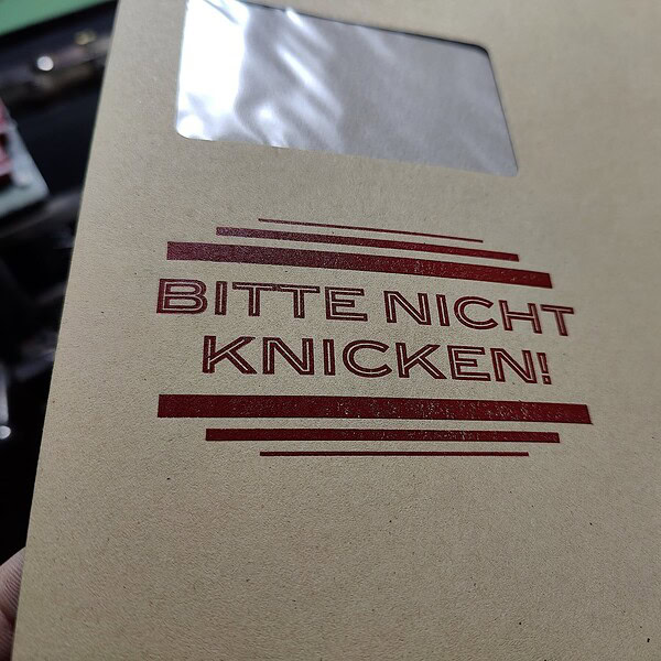 Foto Detail des Hinweis Aufdrucks "Bitte nicht Knicken" in einer Konturschrift zwischen Linien.
