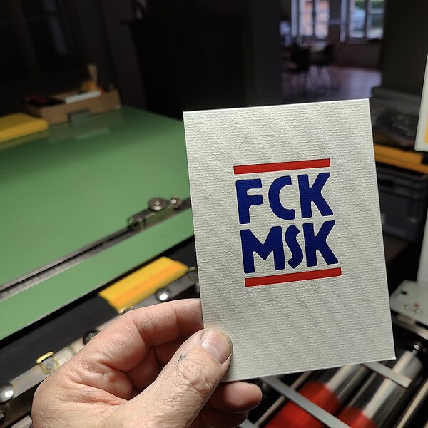 Hand hält FCK MSK Karte vor Druckmaschine.