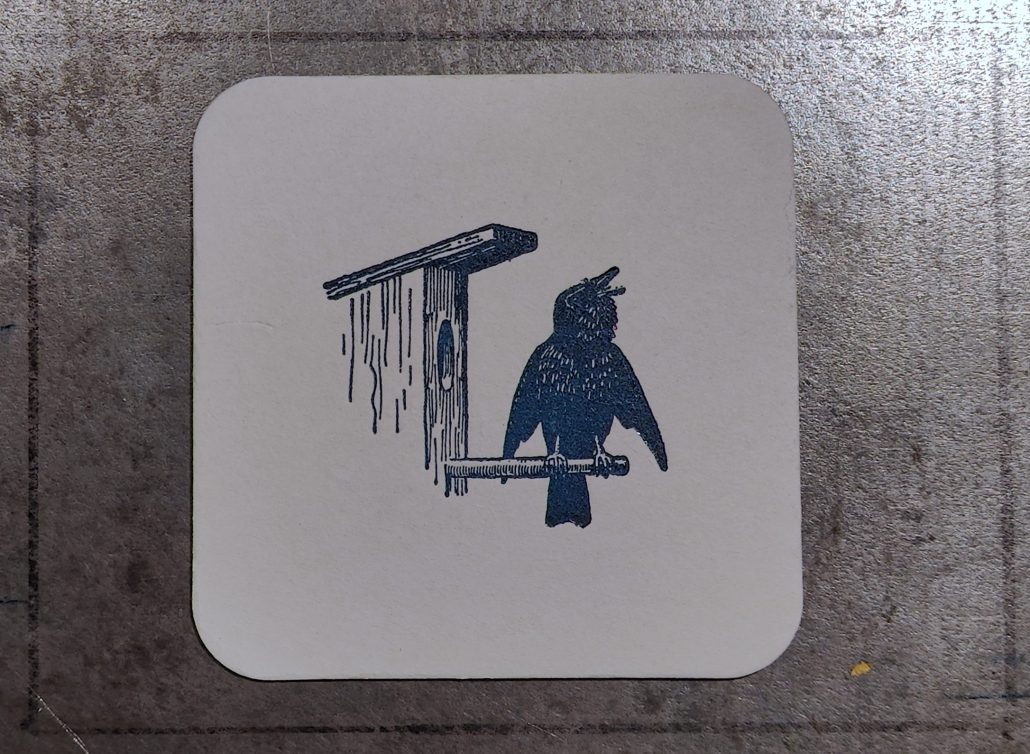 Rabe an einer Wetterfahne auf einem Holzpfahl.