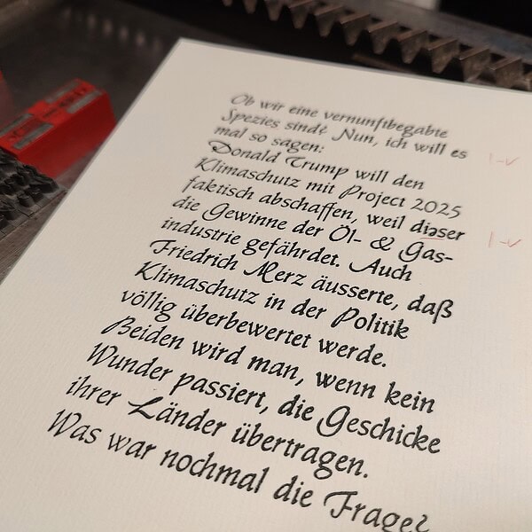 Handgeschriebener Text auf einem weißen Blatt Papier, das auf einer Maschine liegt.