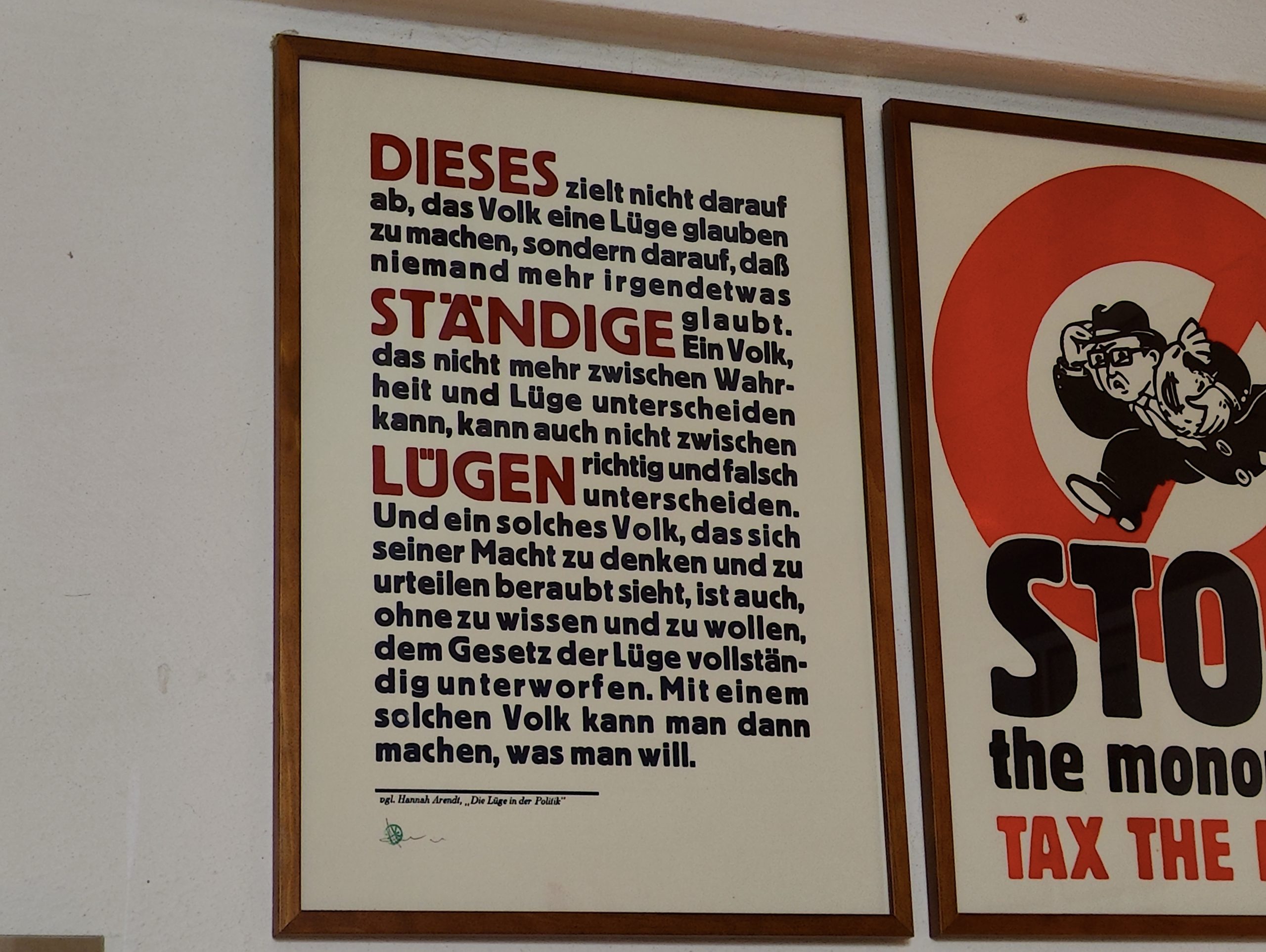 Foto des fertig gerahmten Druckes in Bordaux Rot und Schwarz Blau eines Textes von Hannah Arendt. Der Text lautet: Dieses ständige Lügen zielt nicht darauf ab, das Volk eine Lüge glauben zu machen, sondern darauf, dass niemand mehr irgendetwas glaubt. Ein Volk, das nicht mehr zwischen Wahrheit und Lüge unterscheiden kann, kann auch nicht zwischen richtig und falsch unterscheiden. Und ein solches Volk, das sich seiner Macht, zu denken und zu urteilen, beraubt sieht, ist auch, ohne zu wissen und zu wollen, dem Gesetz der Lüge vollständig unterworfen. Mit einem solchen Volk kann man dann machen, was man will.