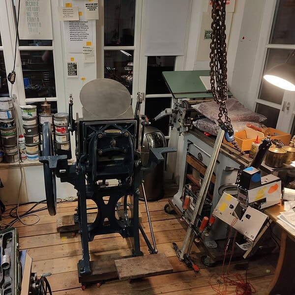 Werkstatt mit alten Werkzeugen und Maschinen, Holzfußboden, Fenster im Hintergrund.
