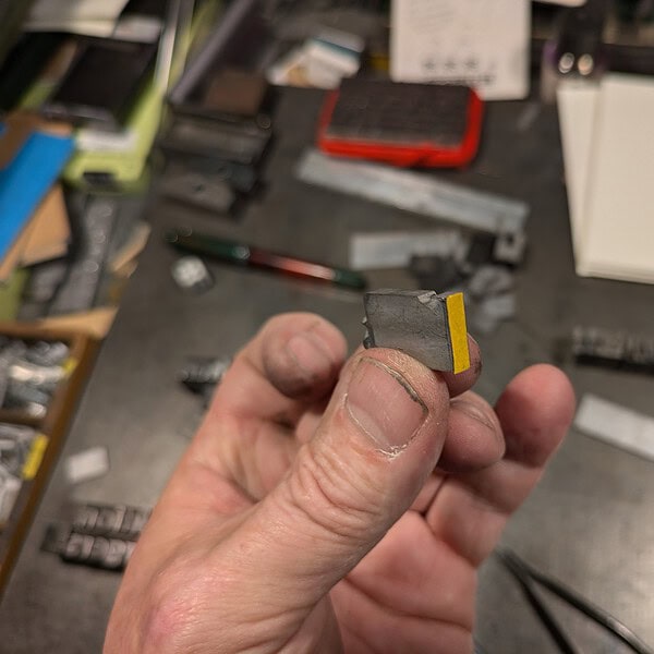 Kleine Metallplatte mit gelber Markierung in Hand gehalten.