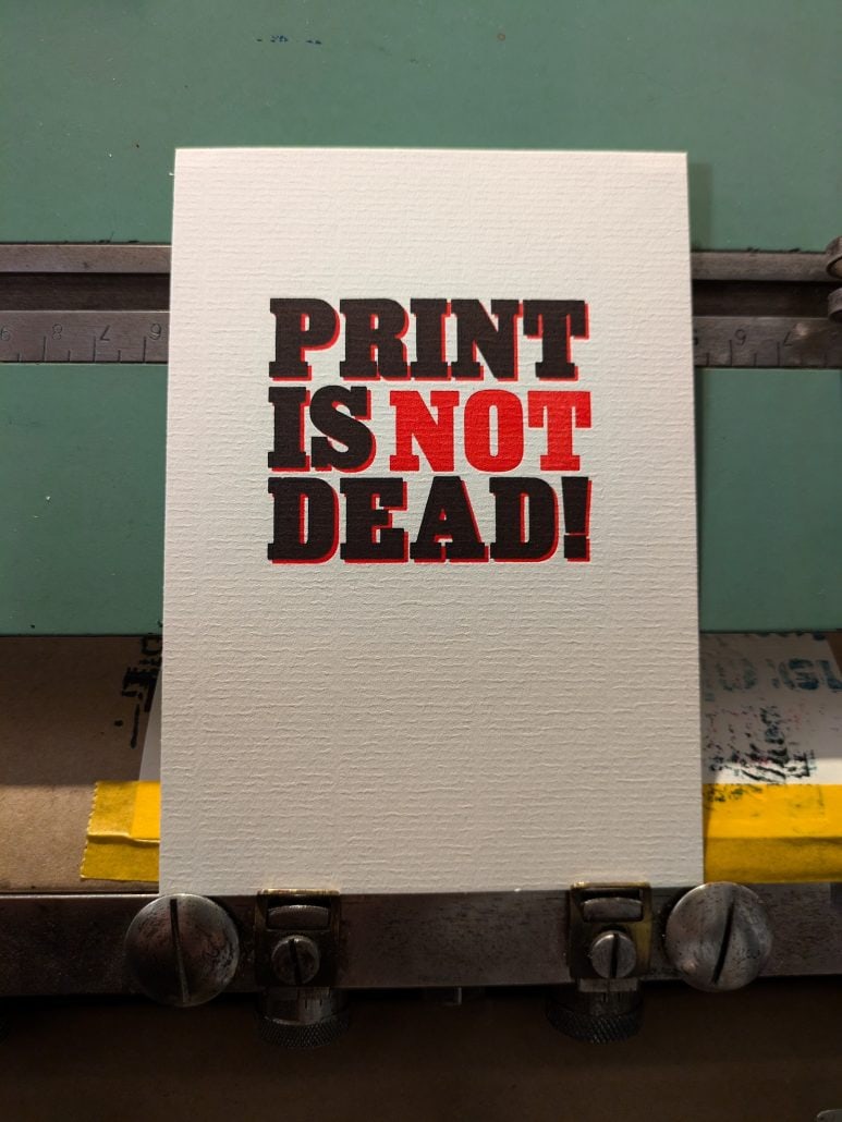 Druckkunst-Poster mit der Aufschrift 'PRINT IS NOT DEAD!'.