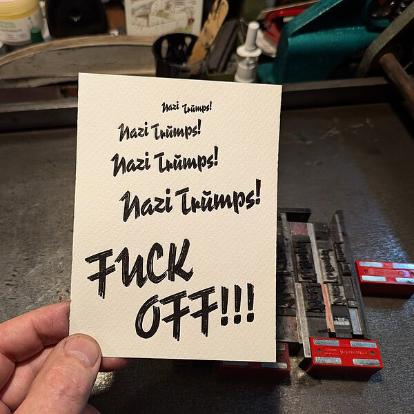 Hand hält ein Protestplakat mit anti-nazistischen Slogans.