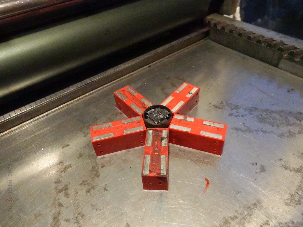 Schweißgerät auf Metallplatte mit roten Abstandshaltern für präzises Schweißen.