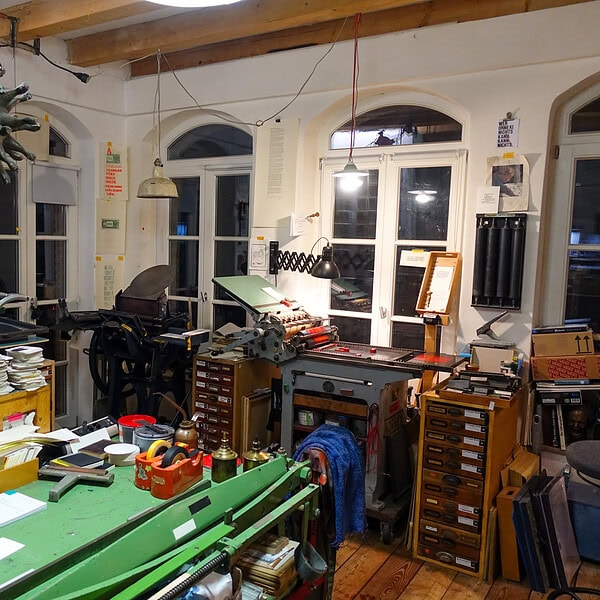 Büro mit vielen Arbeitsmaterialien und technischen Geräten, kreative Arbeitsumgebung.