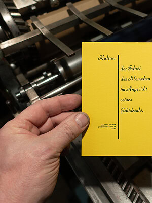Gelbes Buch mit Zitat über Kultur und Schicksal in Hand gehalten.