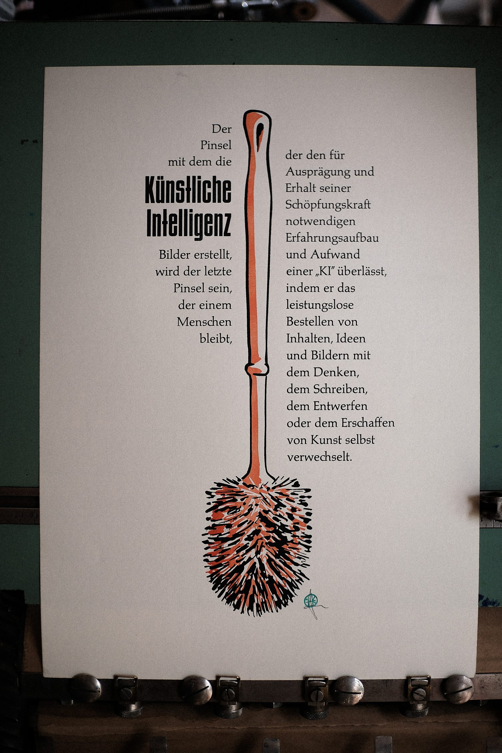 Foto mit dem fertigen Abzug. Man sieht einen Formtext um eine Klobürste. Der Text lautet: Der Pinsel mit dem die Künstliche Intelligenz Bilder erstellt, wird der letzte Pinsel sein, der einem Menschen bleibt, der den für Ausprägung und Erhalt seiner Schöpfungskraft notwendigen Erfahrungsaufbau und Aufwand einer „KI“ überlässt, indem er das leistungslose Bestellen von Inhalten, Ideen und Bildern mit dem Denken, dem Schreiben, dem Entwerfen oder dem Erschaffen von Kunst verwechselt.
