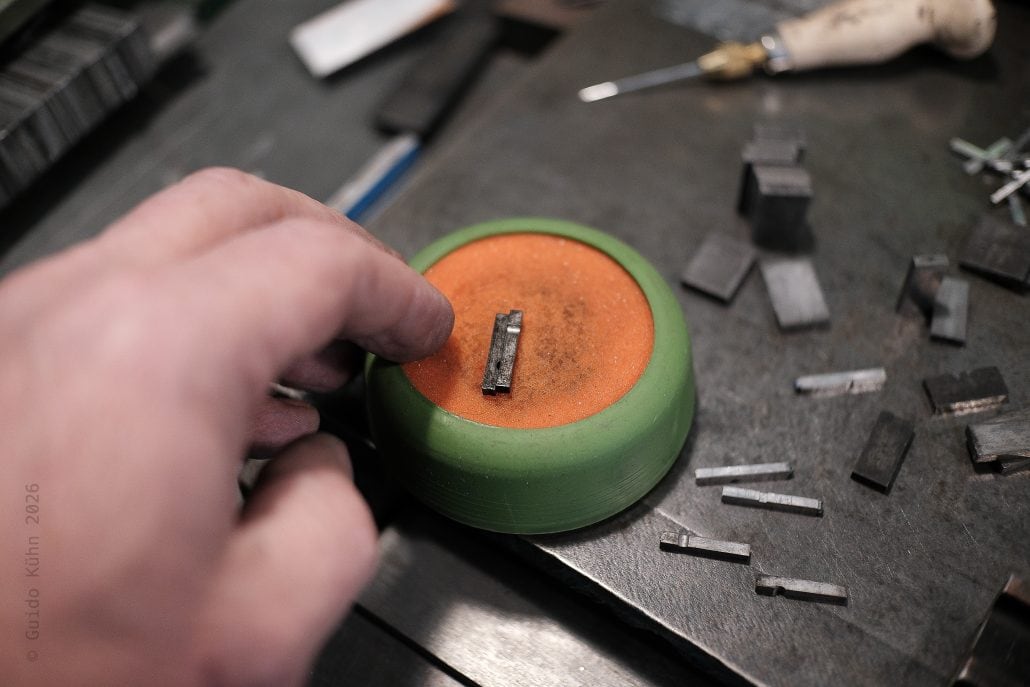 Präzises Arbeiten an einem kleinen Metallstück auf einem grünen Werkzeughalter.