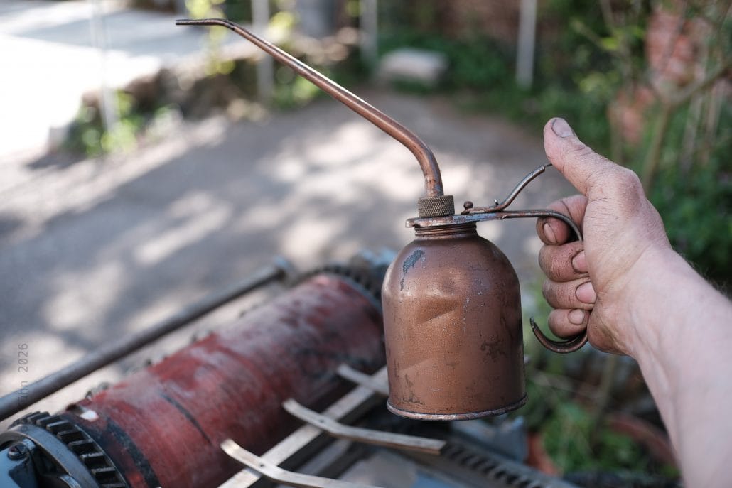 Altes, rostiges Bunsenbrenner in Hand gehalten, Garten im Hintergrund.