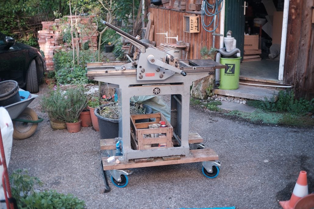 Alte Tischkreissäge auf einem mobilen Werkstattwagen im Garten.