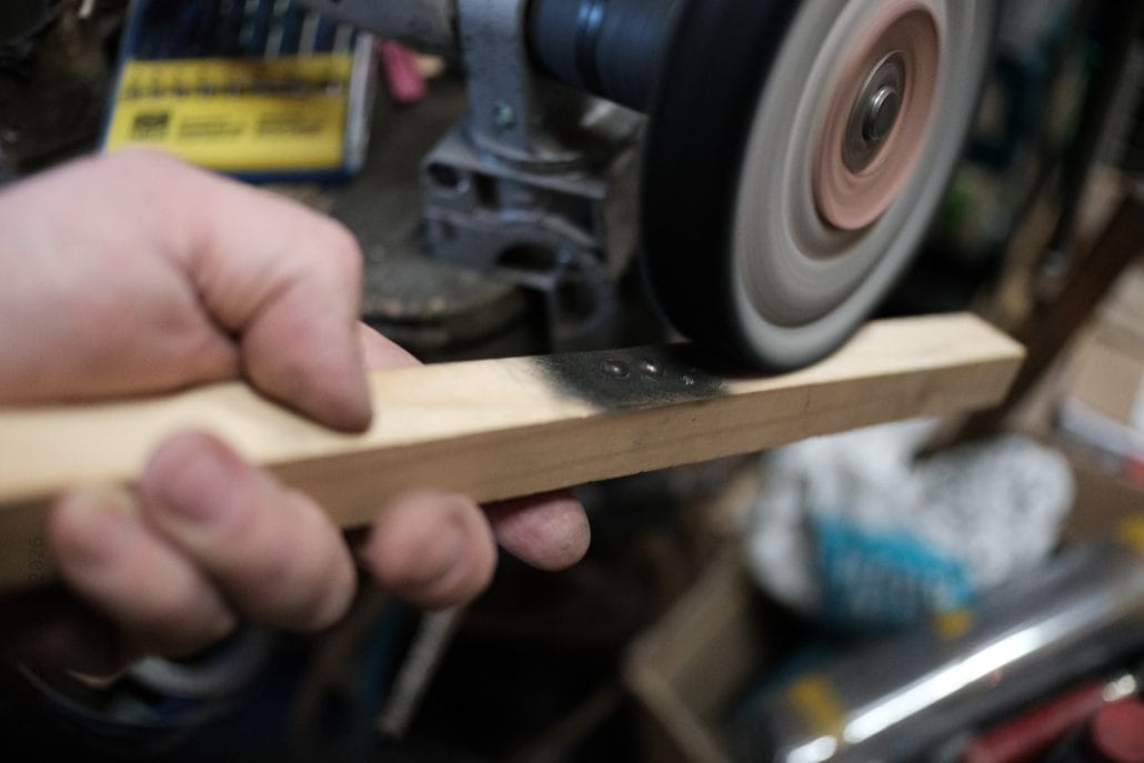 Handschleifen eines Holzstücks mit einer Schleifmaschine in einer Werkstatt.