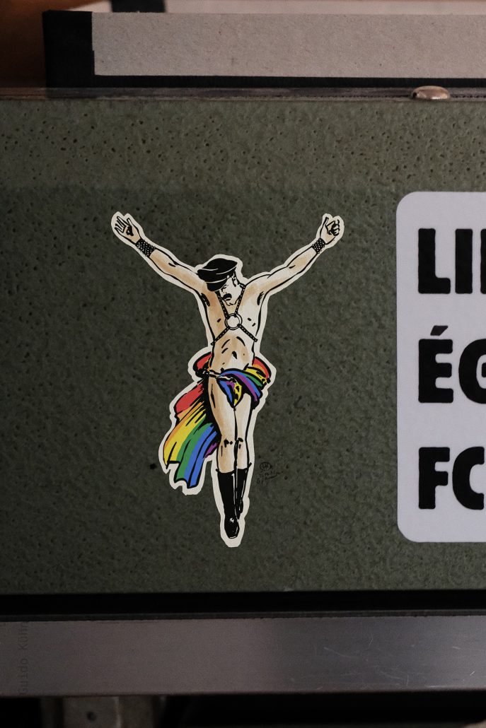 Sticker von Jesus mit Regenbogen-Flagge, symbolisiert Akzeptanz und Vielfalt.